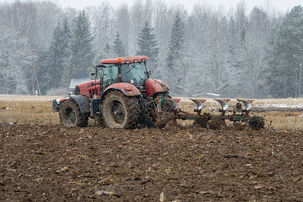istock Red Tractor Plowing Field in Light Winter Snowfall, Agricultural Work in Cold Weather 2248266410