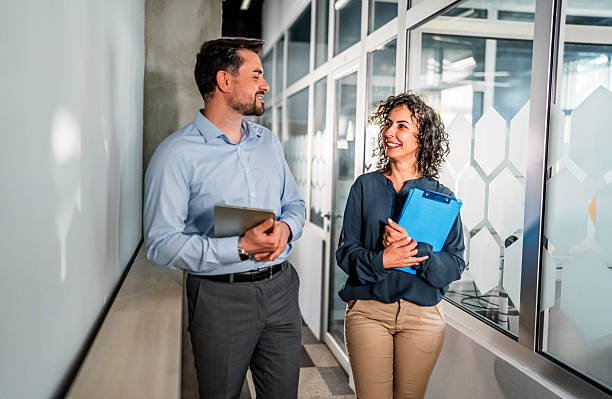 istock Business colleagues walking and talking in office hallway 2248267500