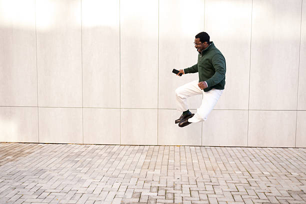 istock Happy man jumping in air holding phone 2248267792