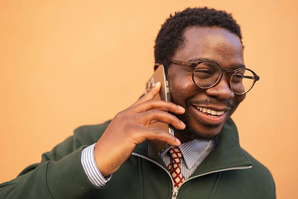 istock Happy man having phone call outdoors against orange background 2248267807
