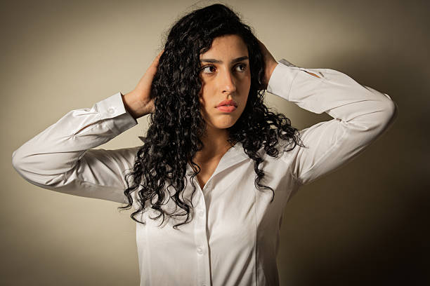Young woman covering ears experiencing stress, anxiety, or a bad headache