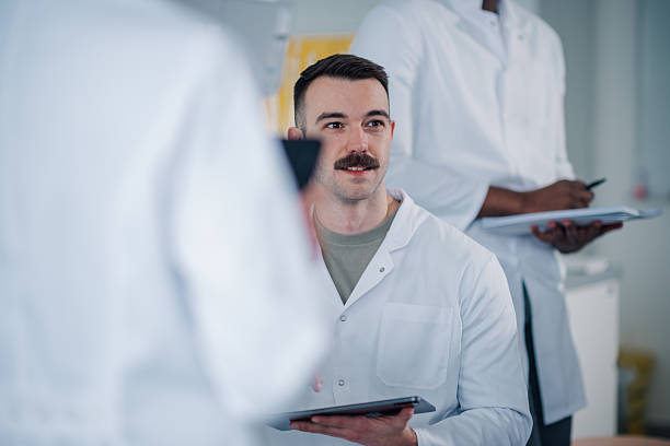 istock Male scientist in lab coat discussing research holding digital tablet 2248270007