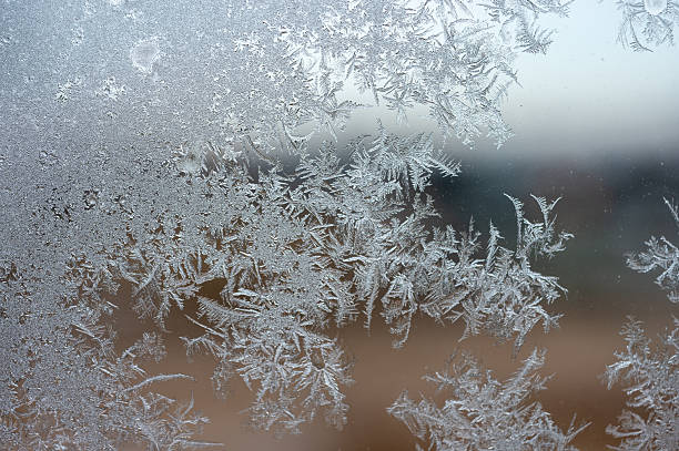 istock Frost crystals covering a window surface with intricate winter ice patterns and a blurred outdoor background. 2248271088