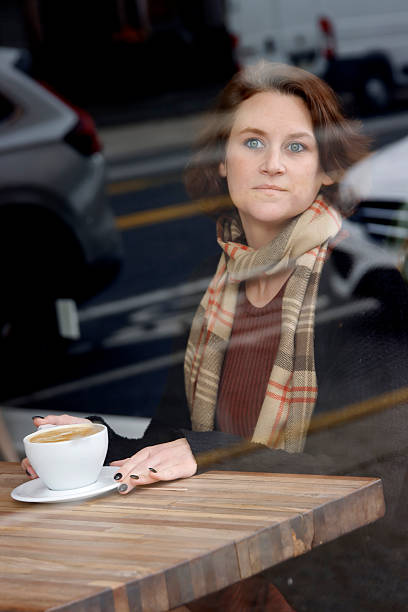 istock Woman drinking coffee in cafe looking out window 2248271651