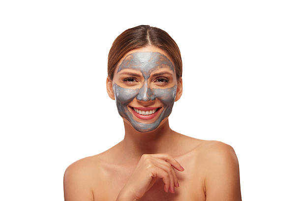 istock Smiling woman applying a revitalizing silver clay mask on her face 2248274886