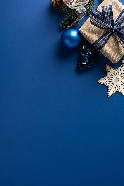 istock Blue vertical backdrop with a wrapped gift, pine sprig, blue ornament, and wooden star evokes festive holiday mood perfect for Christmas and New Year content 2248277535