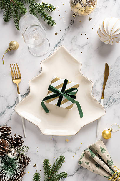 istock Elegant vertical festive table scene with glass, pine branches, gift on a star plate, pine cones, and gold accents creating a warm, sophisticated Christmas mood and holiday greeting 2248277543