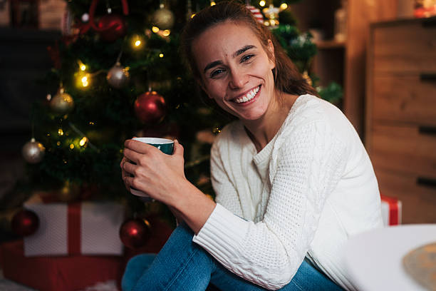 istock Happy woman smiling relaxing by christmas tree 2248278131