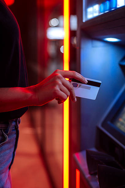 istock Person Using Card At ATM With Red Neon Lighting In Urban Night Scene 2248279875