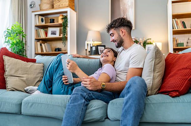 istock Happy couple relaxing at home scrolling on digital tablet 2248280062