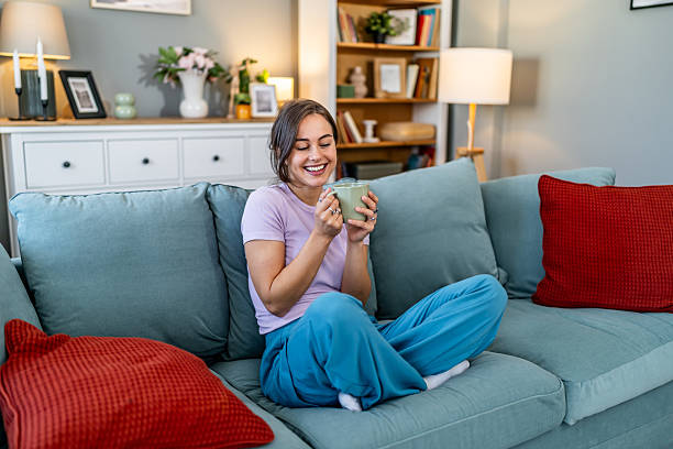 istock Happy young woman relaxing on sofa drinking coffee 2248280838