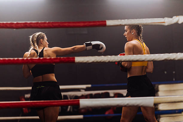 Two female boxers exchange punches in a boxing ring, focused, athletic, and competitive