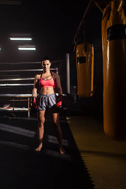 istock Female boxer stands ready in boxing gym spotlight 2248280955