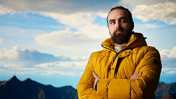 Hiker stands victorious on a mountain peak with arms raised in triumph, celebrating his personal achievement with a successful climb. Scenic view and endless sky for freedom. Camera A.