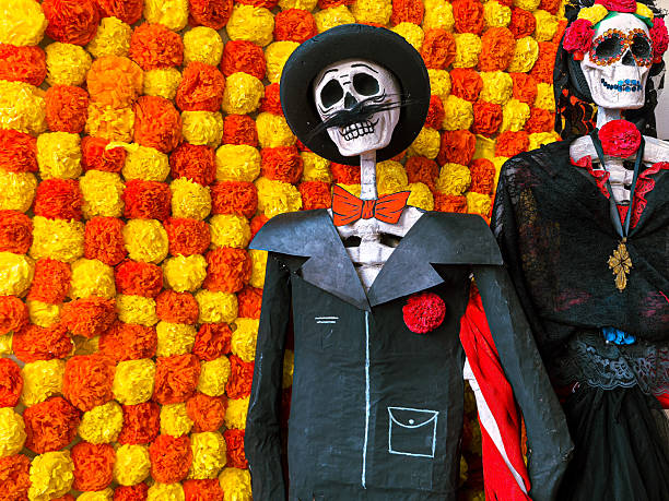 istock Traditional Calavera Figures (Catrín and Catrina) in Front of Flowers 2248281647