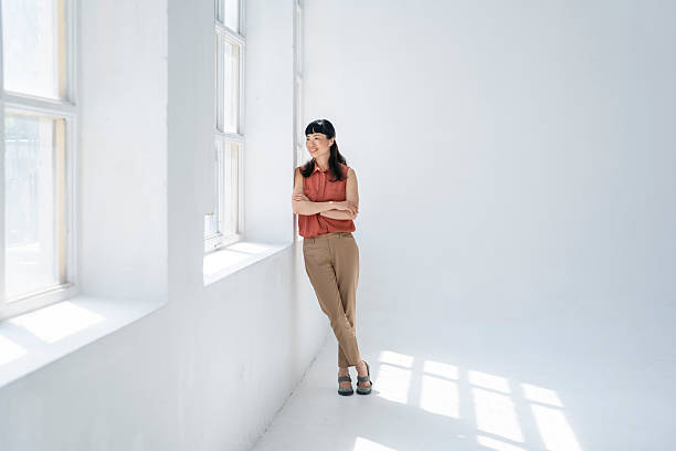 istock Confident businesswoman leaning against wall in modern office 2248285406