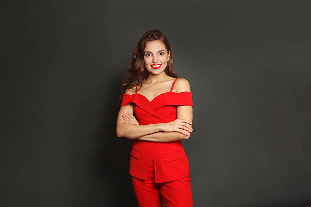 istock Happy young woman in red suit standing against black studio wall background 2248285490