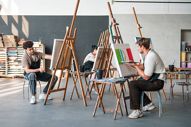 istock Young Artists Working at Wooden Easels in Sunlit Modern Art Studio Space 2248286758