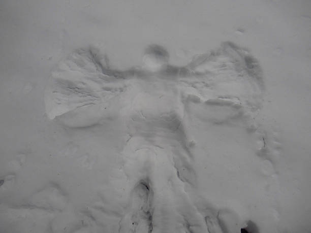 High quality stock photos of two kids playing outside during winter making snow angels.