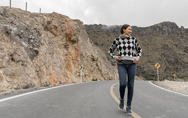 Young adult woman walking along a winding mountain road enjoying the journey