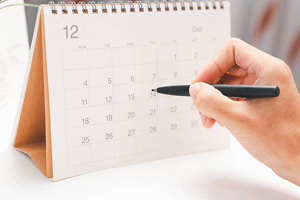 istock Event planner checking yearly schedule on mobile phone with calendar and desk planner, organizing tasks, managing events, and planning work efficiently in a modern office setting. 2248300939