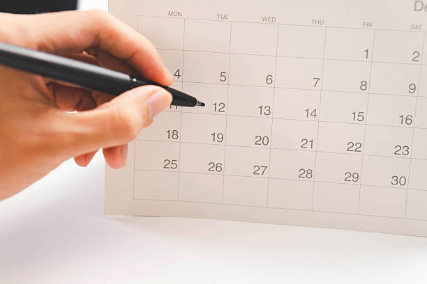 istock Event planner checking yearly schedule on mobile phone with calendar and desk planner, organizing tasks, managing events, and planning work efficiently in a modern office setting. 2248300961