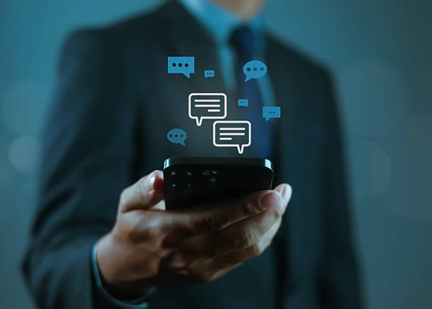 istock Businessman holding smartphone with chat bubbles, symbolizing online communication, instant messaging, customer support, digital conversation, business chat, mobile technology, and virtual connection. 2248304233
