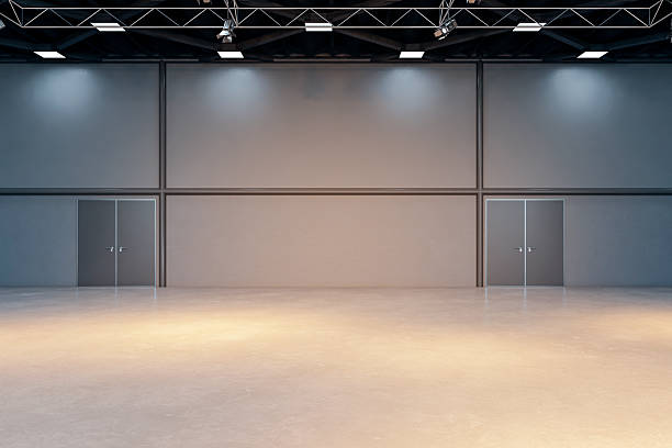 istock Empty modern warehouse interior with polished concrete floor, industrial lights, and dual metal doors under high ceiling structure. 3D Rendering 2248309491