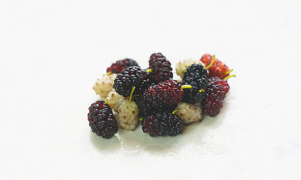 A pile of white and red mulberries stands on a white marble table.