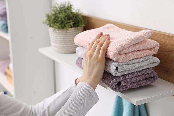 istock Woman stacking clean towels on shelf indoors, closeup 2248314008