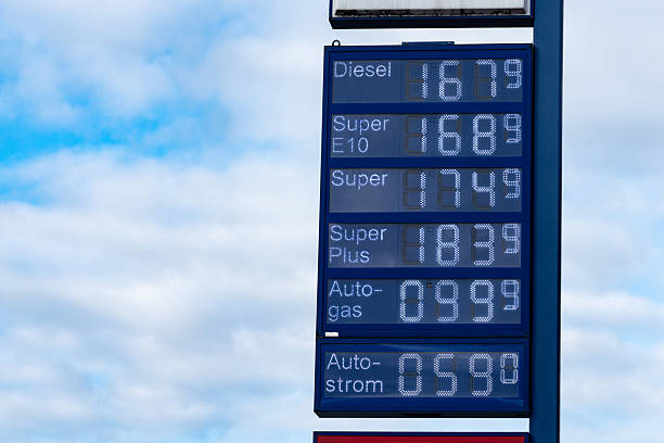 Fuel prices for diesel and various types of gasoline are shown at a gas station. The sky is cloudy, and the scene captures a typical fueling experience for drivers.