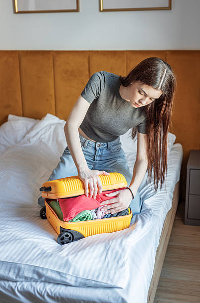 istock Young woman struggling with overstuffed suitcase on bed 2248322759