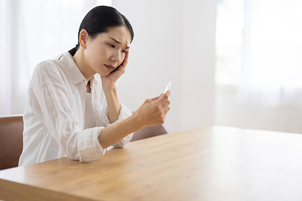istock Woman Looking at Thermometer with a Painful, Worried Expression 2248323557