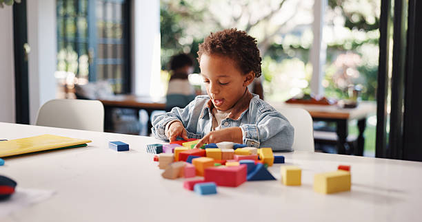 istock Learning, kid or game with building blocks in home for fine motor skills, problem solving or creativity. Education, african boy and wooden toys for sensory play, cognitive development or coordination 2248323800
