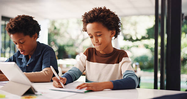 istock Tablet, homework and kids in house with education, learning or studying for test together. Writing, tech and boy children with knowledge for school assignment, assessment or exam by desk in apartment 2248323812
