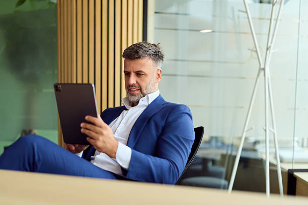 istock Confident Businessman in a Blue Suit Using a Tablet in a Modern Office Environment 2248324716