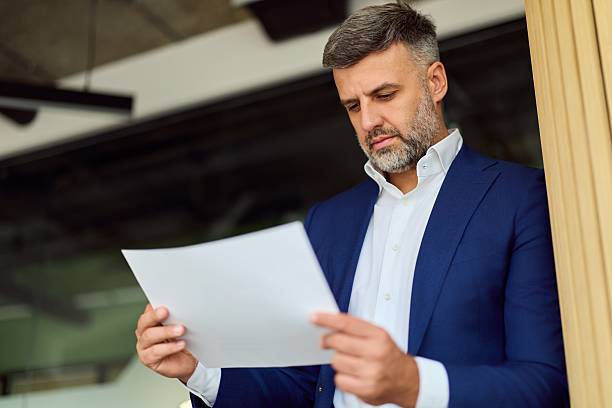 istock Businessman In Navy Suit Reading Document At Modern Office Entrance For Stock Use 2248324729