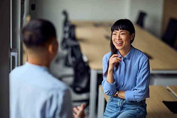 istock Asian Woman And Asian Man Share Friendly Conversation In Modern Office Workspace 2248324733