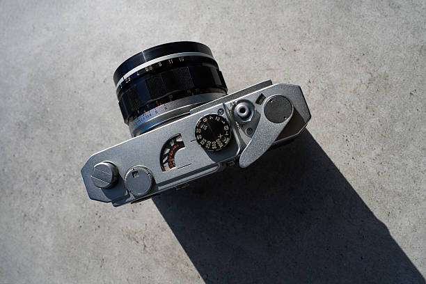 A close-up of an old film camera focusing on the lens, set against a black background. Perfect for celebrating Photographer's Day.