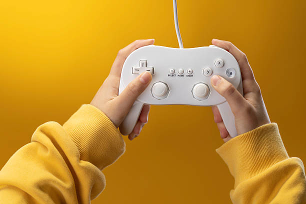 Hands of a Kid Holds White Game Controller Joystick Over Bright Yellow Background for Gaming Action Play Fun Moments