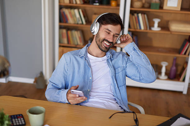 istock Young man listening to music while working from home office 2248333716