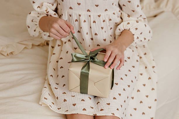 istock Hands Opening a Wrapped Gift Box with Green Ribbon 2248337226