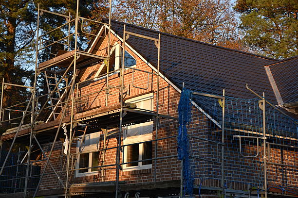Workers are completing the final touches on a new building, with a decorative wreath placed on the roof's peak.