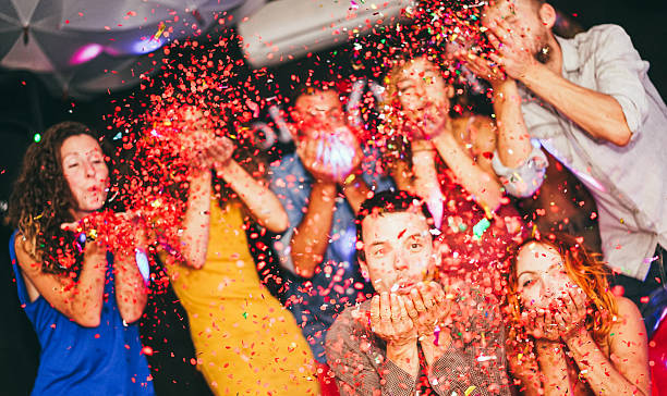 istock Young friends having party throwing confetti - Young people celebrating on weekend night - Entertainment, fun, new year's eve, nightlife, holidays, concept - Soft focus on bottom man's hands 2248343600