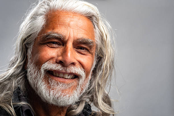 Portrait of a Latin-American senior man with beard and long hair. Cheerful.  Studio shot.