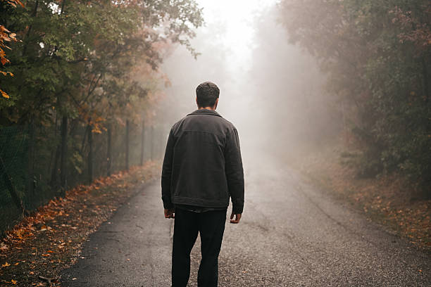 istock Man walking lonely road into dense fog 2248344498
