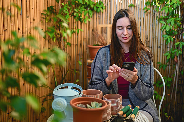 istock Woman using smartphone while urban gardening on balcony 2248345885