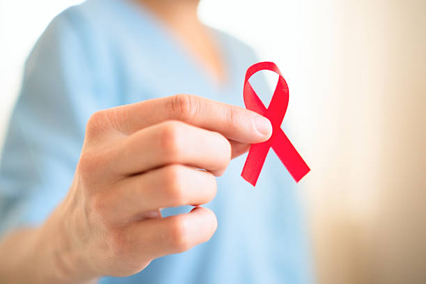 istock Close up hand holding red AIDS ribbon 2248350016