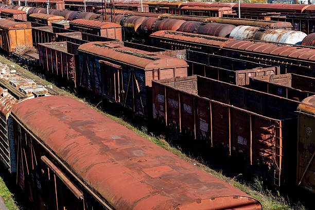 istock Rows of old, rusted freight train cars stand idle in a rail yard, creating a textured pattern of weathered metal and rich earthy tones. 2248352874