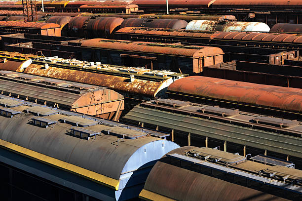 Aerial view of weathered, rusted train carriages lined up in a rail yard, highlighting textures, colors, and industrial decay. Ideal for transportation, history, or urban themes.